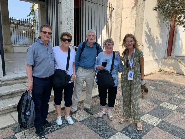 Grupo de clientes sorridentes em frente a uma igreja histórica de Lisboa