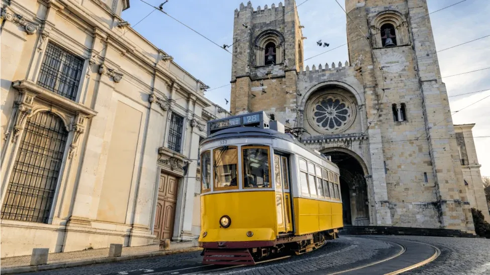 O icónico elétrico amarelo 28 de Lisboa passando em frente à histórica Sé de Lisboa